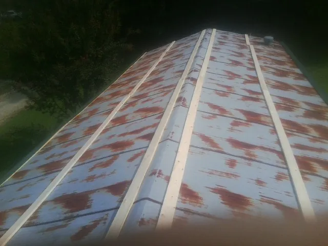 Rusted metal roof panels with new wood purlins before replacement — Storm Damage Roof Repair in La Porte City by Roofing Brothers
