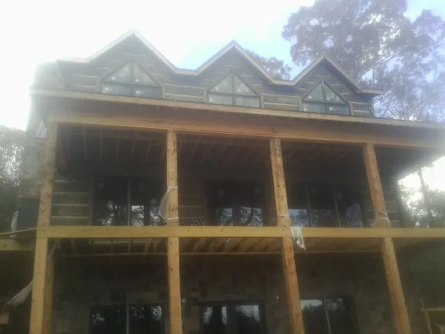 Dormers and porch framing on a large log home under construction — Roof Coating work by our crew in La Porte City