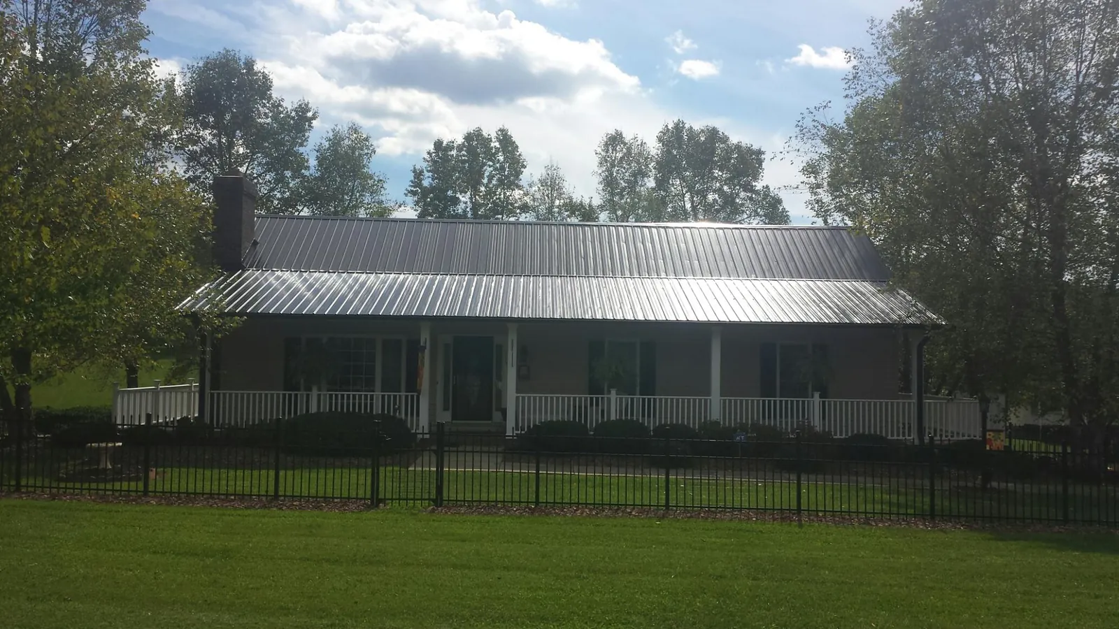 Gray metal roof on a brick ranch with a full width front porch — Gutter Guard Installation work by our crew in La Porte City