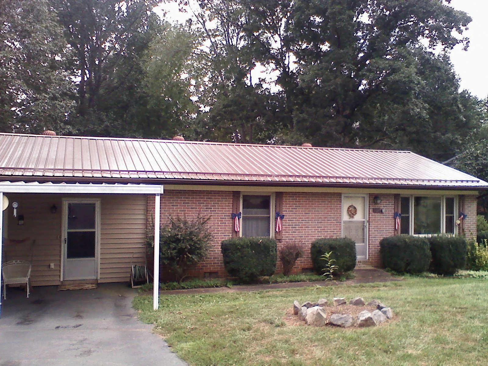 Bronze metal roof and carport on a brick ranch home — Roof Repair work by our crew in La Porte City