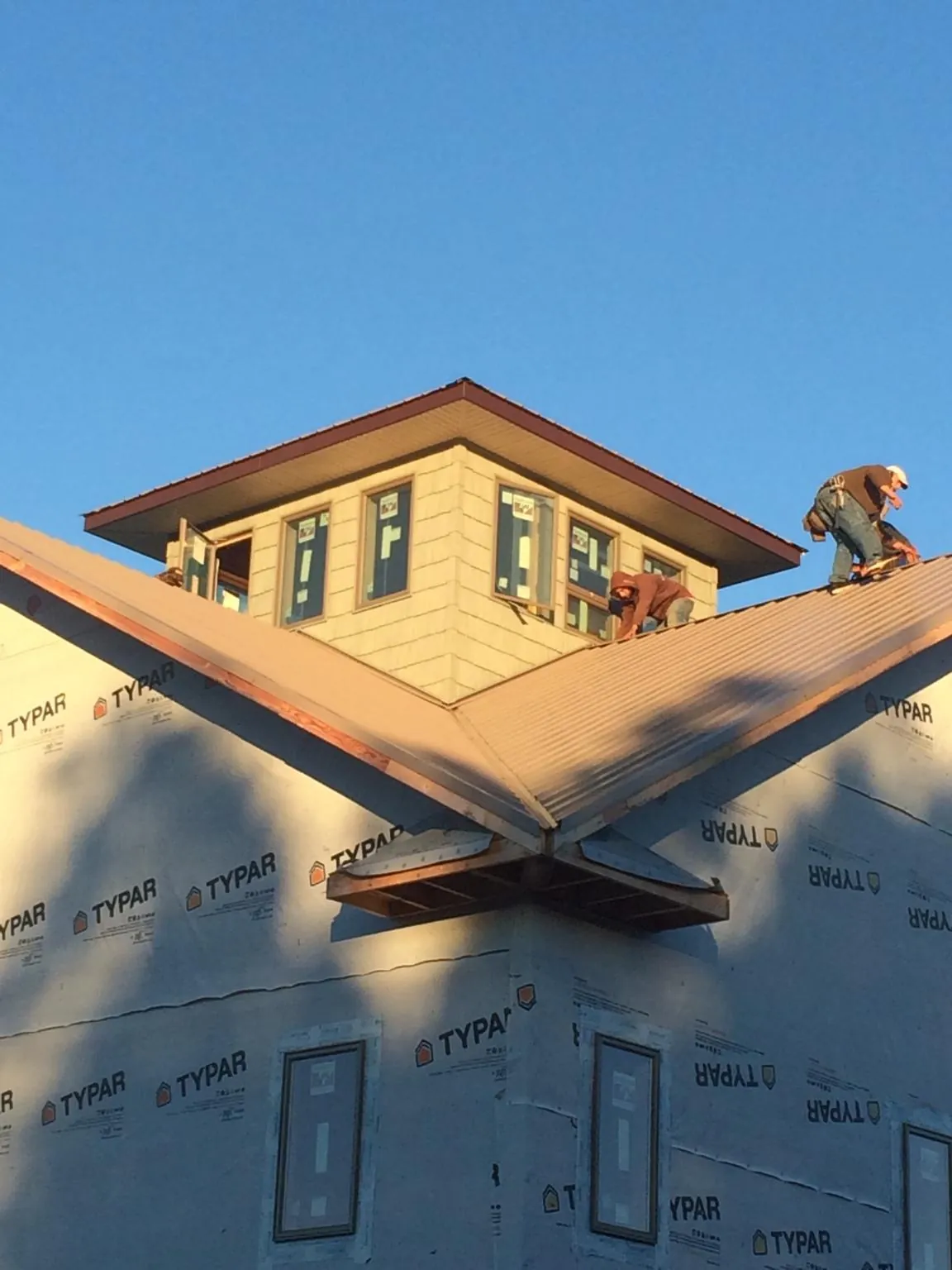 Roofers working around a rooftop cupola on a new metal roof at sunset — Roof Waterproofing in La Porte City by Roofing Brothers